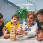 A joyful family moment with grandma and grandsons playing Jenga indoors, capturing quality time together.